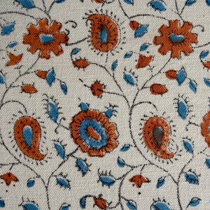 May include: A woven fabric featuring a repeating pattern of orange and blue floral and paisley motifs on an off-white background. The design includes thin black stems connecting the stylised flowers and teardrop shapes across the textile surface.