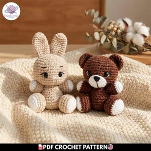 Puede incluir: Dos animales de peluche tejidos a mano, un conejo beige claro y un oso marrón oscuro, ambos con detalles blancos en las patas y orejas. El oso tiene un hocico blanco y nariz negra. Ambas figuras tienen ojos redondos de plástico oscuro.