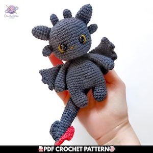 Puede incluir: Un dragón de peluche tejido a ganchillo en color gris oscuro con grandes ojos negros, iris amarillos, alas pequeñas y una cola con una punta de color rojo brillante. El juguete tiene una superficie de hilo texturizado y es un patrón PDF de Crocheverse Store.
