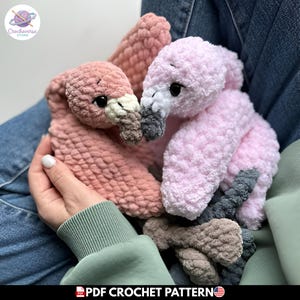 Puede incluir: Dos juguetes de peluche con forma de flamenco hechos de hilo suave y texturizado. Un flamenco es de color rosa viejo con pico crema y marrón, mientras que el otro es rosa claro con pico blanco y gris oscuro. Ambos tienen ojos negros.