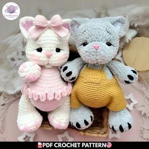 Puede incluir: Dos muñecos de gato de ganchillo. Uno es blanco con detalles rosas, un lazo y un vestido rosa. El otro es gris y lleva un peto amarillo. Ambos tienen patas y rasgos faciales negros. La imagen incluye el texto "PDF CROCHET PATTERN".