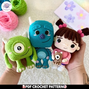 Puede incluir: Figuras de ganchillo de Mike Wazowski, Sulley y Boo de Monstruos S.A. El Mike verde tiene un ojo, el Sulley azul tiene cuernos y Boo lleva un atuendo rosa y sostiene un osito de peluche. La imagen incluye el texto "PDF CROCHET PATTERN".