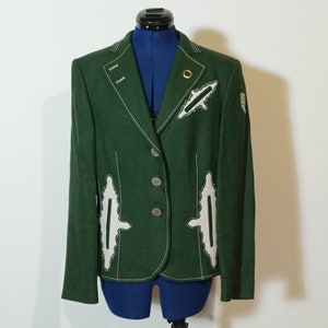 May include: A dark green blazer with white stitching and decorative details. The blazer has a button closure and a pointed collar.