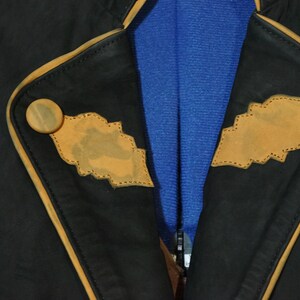 May include: A black leather jacket with brown leather trim and stitching. The jacket has two decorative brown leather patches on the front.