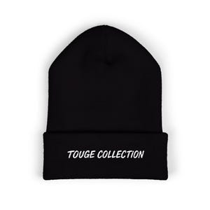 May include: Black beanie hat with the white embroidered text "TOUGE COLLECTION" on the folded brim. The hat is a solid black colour and appears to be made of a soft, knitted material.