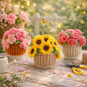 Puede incluir: Tres arreglos florales de ganchillo en macetas texturizadas. La maceta izquierda es naranja con flores rosas, la central es beige con girasoles amarillos y la derecha es beige con rosas rosas. Una pequeña regadera blanca y unas tijeras amarillas.