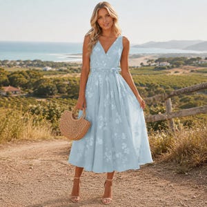 May include: A light blue midi dress featuring a V-neckline, a wrap-style bodice with a side tie, and a subtle white floral pattern. The dress has a sleeveless design with a full, flowing skirt that falls below the knees, paired with a woven straw handbag.