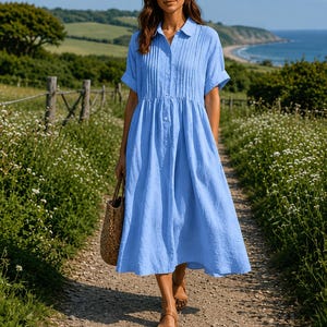 May include: A light blue midi-length shirt dress featuring a collared neckline, a button-down front, short sleeves with folded cuffs, and vertical pleat detailing on the bodice. The dress has a relaxed fit with a gathered waistline and a full skirt.