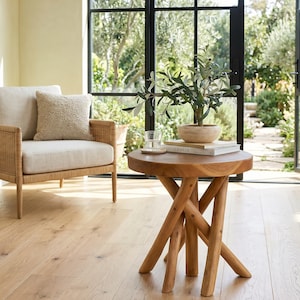 May include: A round wooden side table with a smooth top and a base constructed from several intersecting, angled cylindrical legs. The table is crafted from light brown wood and features a natural grain finish throughout its entire structure.