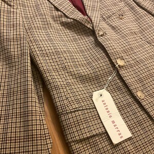 Puede incluir: Una blazer a cuadros beige y negro con forro burdeos. La blazer presenta un dise&ntilde;o cl&aacute;sico con botones y una etiqueta que dice "antonio marras". La chaqueta es de corte entallado.