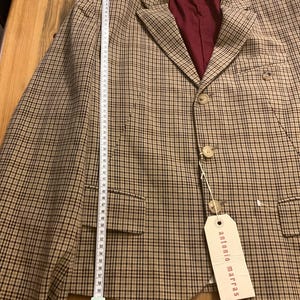 Puede incluir: Una blazer a cuadros marr&oacute;n y beige con forro burdeos. La blazer tiene dos bolsillos delanteros y tres botones. Una cinta m&eacute;trica muestra que la blazer mide aproximadamente 58 cm de largo. La etiqueta dice "antonio marras".