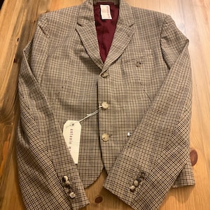 Puede incluir: Una blazer a cuadros marr&oacute;n y negro con forro burdeos. La blazer tiene tres botones en cada pu&ntilde;o y dos en la parte delantera. Una etiqueta con el texto "antonio m" est&aacute; adjunta.