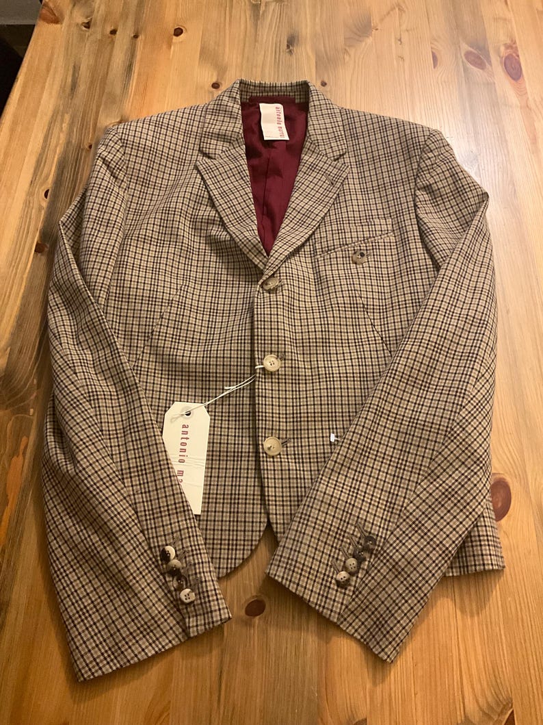 Puede incluir: Una blazer a cuadros marr&oacute;n y negro con forro burdeos. La blazer tiene tres botones en cada pu&ntilde;o y dos en la parte delantera. Una etiqueta con el texto "antonio m" est&aacute; adjunta.