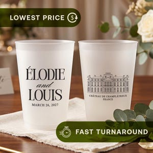 May include: Two frosted plastic cups featuring black printed text and graphics. One cup displays the names Élodie and Louis with the date March 26, 2027. The other cup shows a detailed line drawing of a building labelled Château de Champlâtreux France.