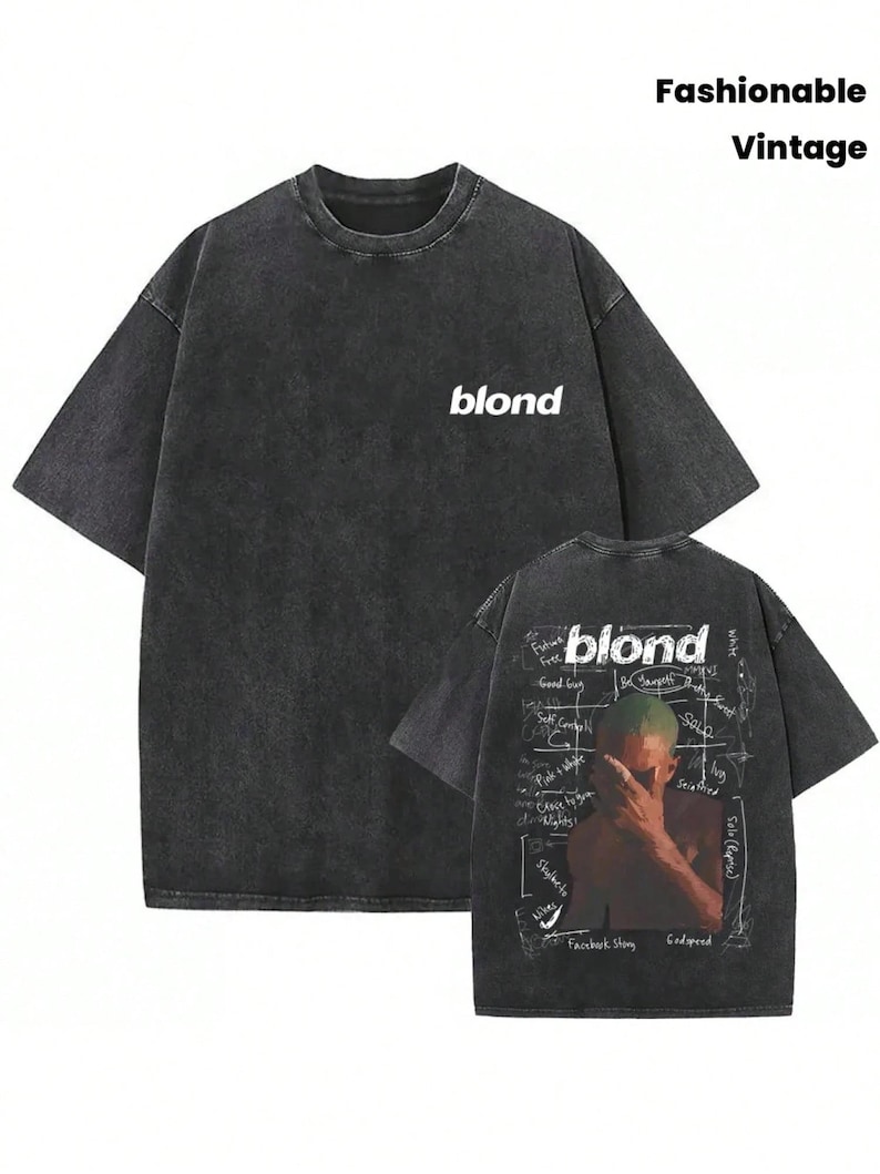 May include: A charcoal gray short-sleeve t-shirt with a washed finish. The front features the word "blond" in white. The back displays a graphic of a person covering their face with text including "blond," "Godspeed," and "Facebook Story."