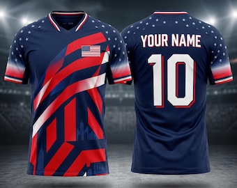 May include: A navy blue soccer jersey with a V-neck and red and white accents. The front features a stylized American flag design and the US flag. The back displays "YOUR NAME" above the number "10".