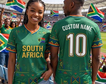 May include: Two people wearing green South Africa soccer jerseys. The jerseys have the words "SOUTH AFRICA" and the South African flag on the front. The back of the jersey has the number 10 and the words "CUSTOM NAME".