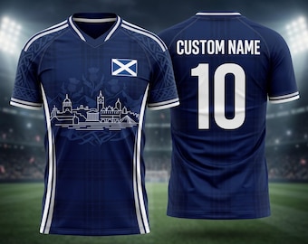 May include: Navy blue soccer jersey with white accents. The front features a Scottish flag and a white line drawing of a cityscape. The back displays "CUSTOM NAME" above the number "10" in white.