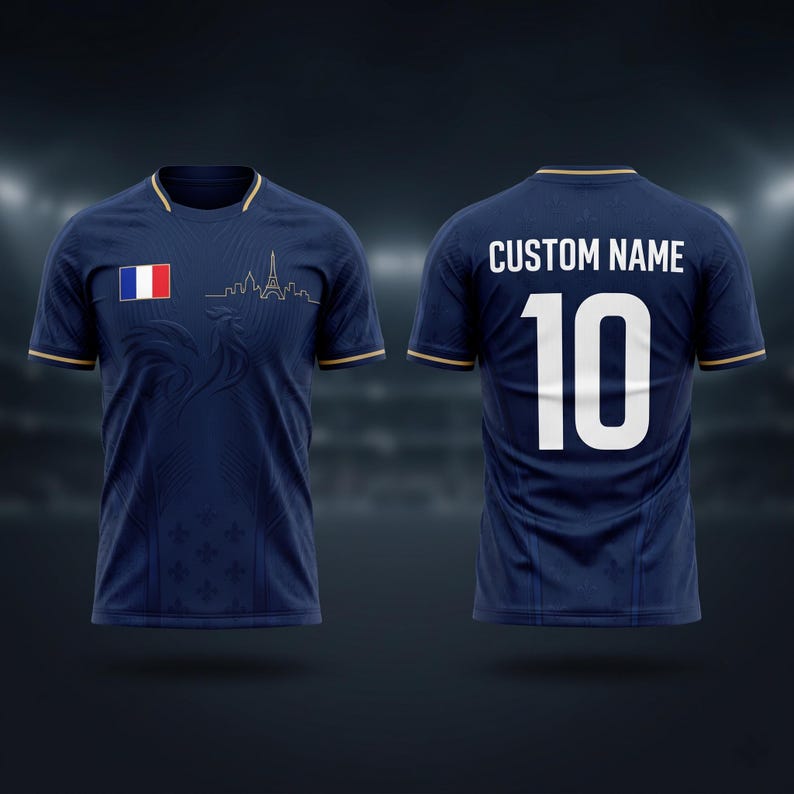 K&ouml;nnte beinhalten: Marineblaues Fu&szlig;balltrikot mit goldenen Verzierungen, das die franz&ouml;sische Flagge und die Umrisse des Eiffelturms zeigt. Die Vorderseite zeigt ein dezentes Muster und die Nummer 10 auf dem R&uuml;cken, mit "CUSTOM NAME" dar&uuml;ber. Ein stilvolles Design f&uuml;r Sportbegeisterte.