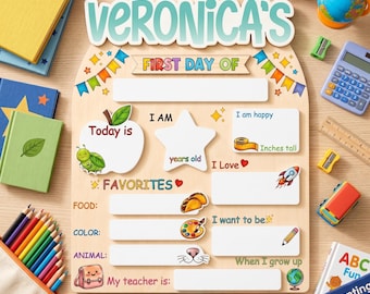 May include: A light-colored wooden sign with the text "VERONICA'S" at the top, featuring sections for "FIRST DAY OF," "I AM," "FAVORITES," and "When I grow up." The board includes blank white spaces for writing, decorated with colorful illustrations of an apple, a star, a rocket, tacos, a paint palette, and a pencil.