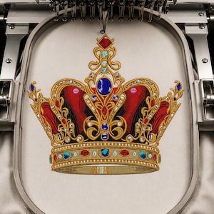 Könnte beinhalten: Ein Stickmaschinenrahmen hält ein Stück cremefarbenen Stoff mit einem detaillierten, maschinengestickten Design einer goldenen Krone. Die Krone ist mit roten Stoffabschnitten und verschiedenen blauen, roten und weißen runden Edelsteinakzenten verziert.