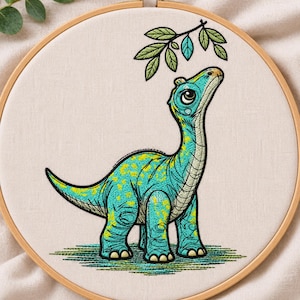 Könnte beinhalten: Ein Stickrahmen mit einem Stoffstück, das ein gesticktes Design eines türkisfarbenen Dinosauriers mit gelben Flecken zeigt. Der Dinosaurier hat einen langen Hals, große Augen und schaut zu einem kleinen Zweig mit grünen Blättern hinauf.