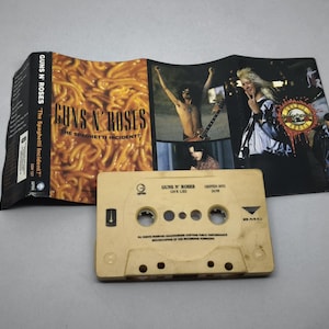 May include: A Guns N' Roses cassette tape and album art. The cassette is beige with text and holes. The album art features a spaghetti image and band members. The album is titled "The Spaghetti Incident?"