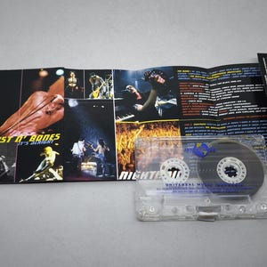 May include: A clear cassette tape with a black and white label, and a folded album cover. The album cover features images of a band performing on stage, with the text "Dust N' Bones It's Alright" and "NIGHTRAIN".