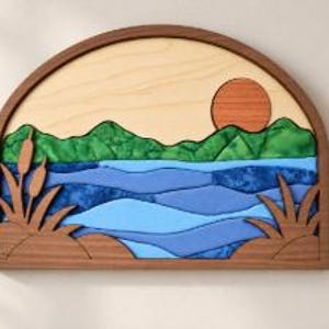 May include: A semi-circular wooden wall art piece featuring a layered landscape scene. The design includes a light wood sky with a reddish-brown sun, green fabric-textured hills, blue fabric-textured water, and brown wooden cattails and grass.