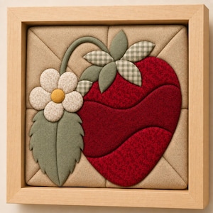 May include: A square fabric wall art piece framed in light wood, featuring a padded, quilted strawberry design in deep red with green leaves, a small white flower with a yellow center, and a beige background with diagonal stitched lines.