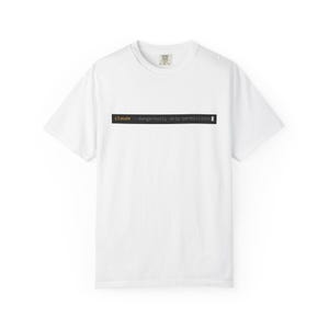 May include: A white short-sleeved t-shirt featuring a black rectangular graphic on the chest. The graphic displays the text "claude --dangerously-skip-permissions" in a monospaced font, with "claude" in yellow and the rest in white.