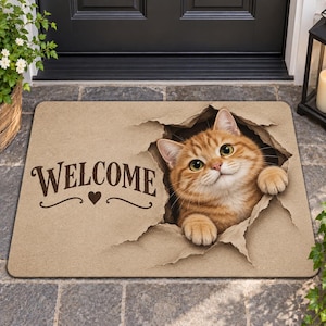 Peut inclure: Un paillasson rectangulaire beige avec une illustration imprimée d'un chat tigré roux qui semble sortir d'une déchirure dans le papier. Le mot WELCOME est écrit en lettres marron foncé avec un petit cœur centré sous le texte à gauche.