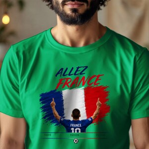 May include: A bright green short-sleeved t-shirt featuring the text "ALLEZ FRANCE" in blue and red. Below the text is a graphic of the French flag and a soccer player wearing a blue jersey with "FRANCE 10" on the back, with the words "FIERT&Eacute;", "PASSION", and "VICTOIRE" below.
