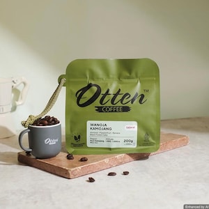 May include: A green 200g coffee bag labelled Otten Coffee Wanoja Kamojang with flavour notes of almond, passionfruit, banana, and black forest cake. Next to it is a small grey mug filled with roasted coffee beans and a yellow patterned cord.