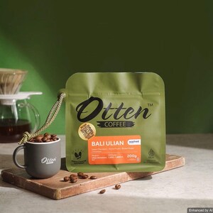 May include: An olive green coffee bag labelled Otten Coffee Bali Ulian 200g with a QR code sticker. Next to it sits a small grey mug filled with roasted coffee beans, featuring the Otten logo. A braided cord is attached to the coffee bag.