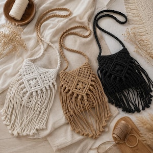 Puede incluir: Tres bolsos bandolera de macramé con correas trenzadas y detalles de flecos largos. Los bolsos están dispuestos en fila, con un bolso blanco a la izquierda, uno beige en el centro y uno negro a la derecha, cada uno con un patrón de rombos.