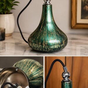 May include: Green and gold pendant light with a teardrop-shaped glass shade. The shade has a crackle finish and is suspended by a black cord. The light fixture has a chrome-colored top.