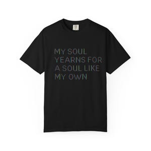 Puede incluir: Camiseta negra con el texto "MY SOUL YEARNS FOR A SOUL LIKE MY OWN" en una fuente pixelada multicolor. La camiseta tiene cuello redondo clásico y mangas cortas. La camiseta está hecha de un material suave.