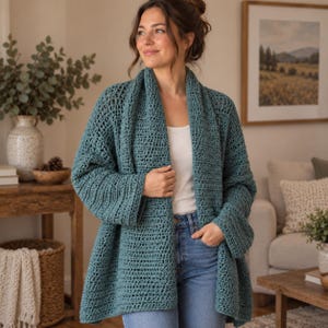 Peut inclure: Un gilet ouvert en crochet bleu sarcelle avec un motif de mailles texturé, des manches longues et un large col châle. Le vêtement est porté sur un haut blanc uni et un jean bleu, présentant une coupe ample et confortable en fil de laine.