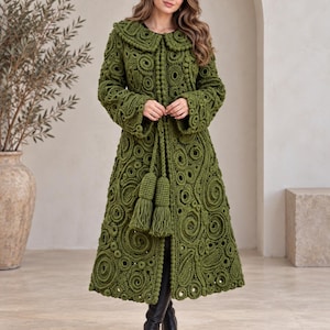 May include: An olive green long-length coat featuring an intricate crochet pattern of circular motifs and raised textures. The garment includes a wide collar, long sleeves, and a front closure secured with two large matching yarn tassels.