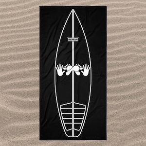 Könnte beinhalten: Ein rechteckiges schwarzes Strandtuch mit einer großen weißen Strichgrafik eines Surfbretts. Das Surfbrett-Design umfasst eine vertikale Mittellinie, ein Kronensymbol, zwei offene Hände, ein Paar gekreuzte Füße und ein segmentiertes Traktionspad.