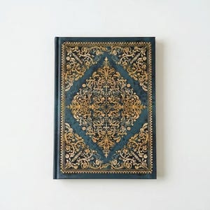 May include: A rectangular notebook with a dark teal cover featuring an intricate gold foil filigree pattern. The design consists of a central diamond-shaped motif surrounded by ornate scrolling vines and floral elements, framed by a decorative border.