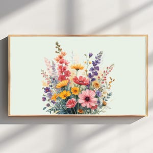 Könnte beinhalten: Ein rechteckiges gerahmtes Wandbild mit einer lebendigen Aquarellillustration eines Wildblumenstraußes. Das Arrangement umfasst rosa, gelbe, orange und violette Blüten mit grünen Stielen und Blättern vor einem hellen cremefarbenen Hintergrund.