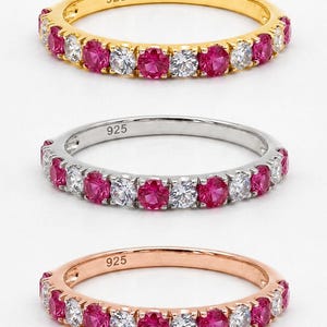 Può includere: Tre anelli d'argento con pietre preziose rosa e chiare alternate. L'anello superiore è dorato, l'anello centrale è argentato e l'anello inferiore è in oro rosa. Ogni anello è contrassegnato con "925".