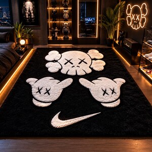 Pode incluir: Um tapete preto de pel&uacute;cia com desenhos brancos de caveiras e m&atilde;os de desenho animado, juntamente com um logotipo Nike branco. O tapete, provavelmente para um quarto ou sala de estar, tem um design moderno e art&iacute;stico.