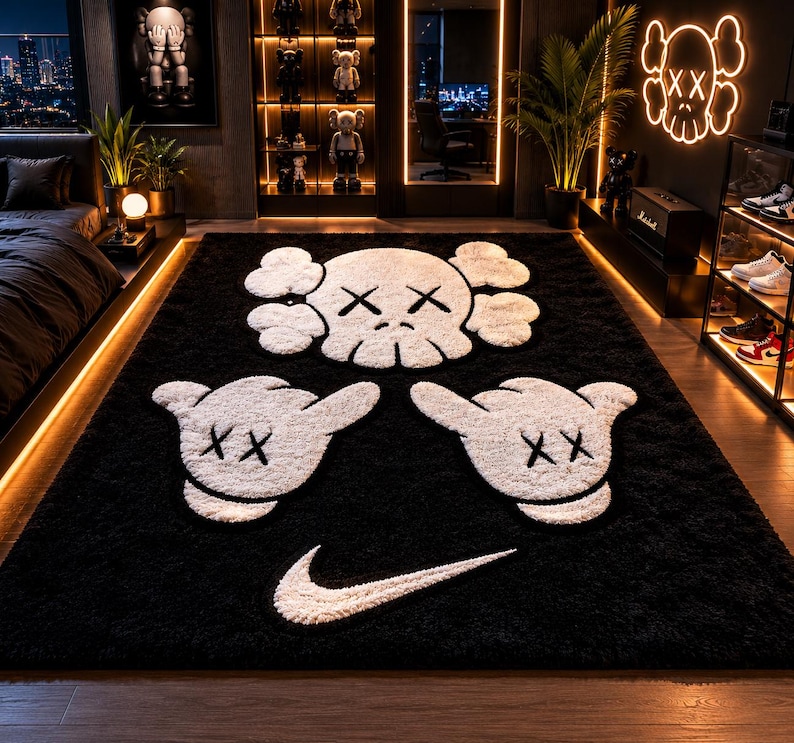Pode incluir: Um tapete preto de pel&uacute;cia com desenhos brancos de caveiras e m&atilde;os de desenho animado, juntamente com um logotipo Nike branco. O tapete, provavelmente para um quarto ou sala de estar, tem um design moderno e art&iacute;stico.