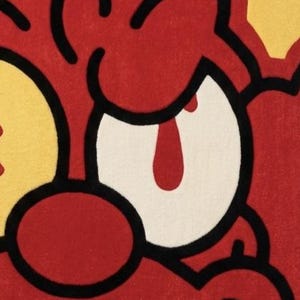 May include: A tufted rug featuring a cartoon-style character face with bold black outlines. The design uses vibrant red, yellow, and white colors, showcasing a large white eye with a red pupil, a red nose, and stylized red facial features.
