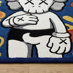 Pode incluir: Um tapete retangular com uma personagem de desenho animado branca com olhos em forma de X e m&atilde;os enluvadas sobre um fundo azul profundo. O design inclui formas abstratas amarelas, laranjas e vermelhas, com o texto KAWS no canto inferior.