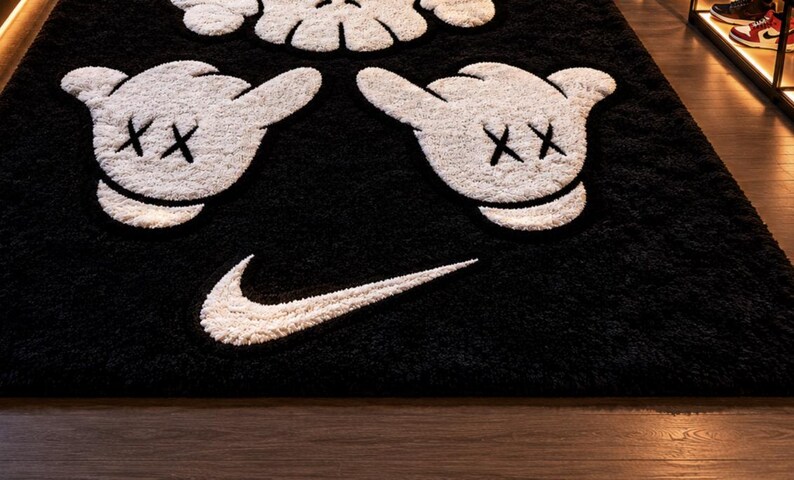 Pode incluir: Tapete de pel&uacute;cia preto e branco com um design de m&atilde;o de desenho animado, detalhes de olhos "XX" e um logotipo da Nike. O tapete tem uma superf&iacute;cie macia e texturizada, adequado para decora&ccedil;&atilde;o de casa.