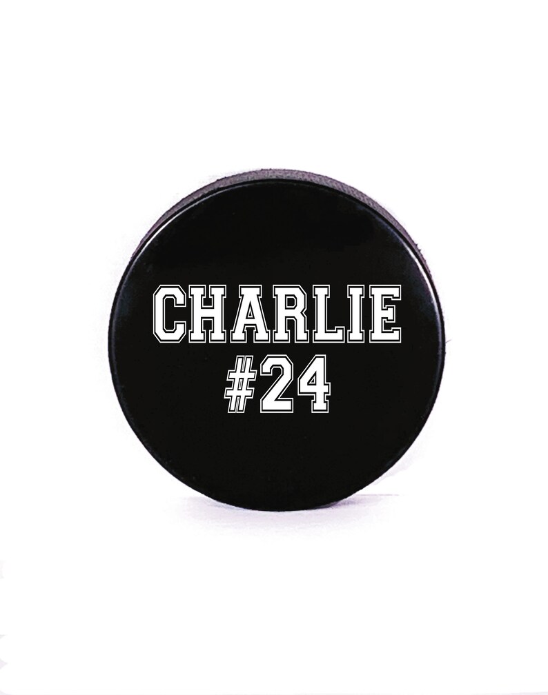 May include: Black hockey puck with white text that reads "CHARLIE #24".